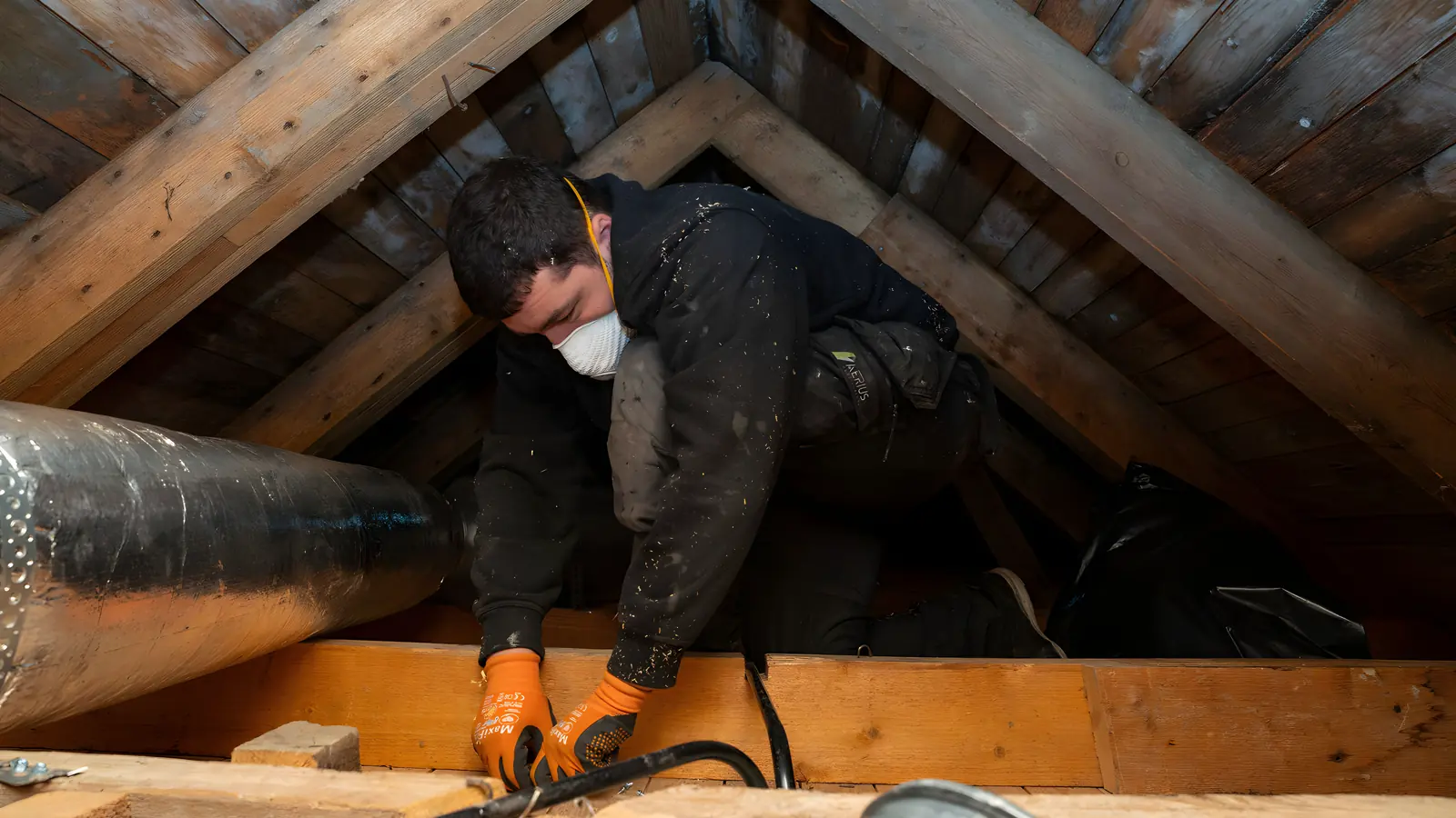 Ventilationstekniker vid en vindslucka under arbete med ventilationskanaler i Stockholm
